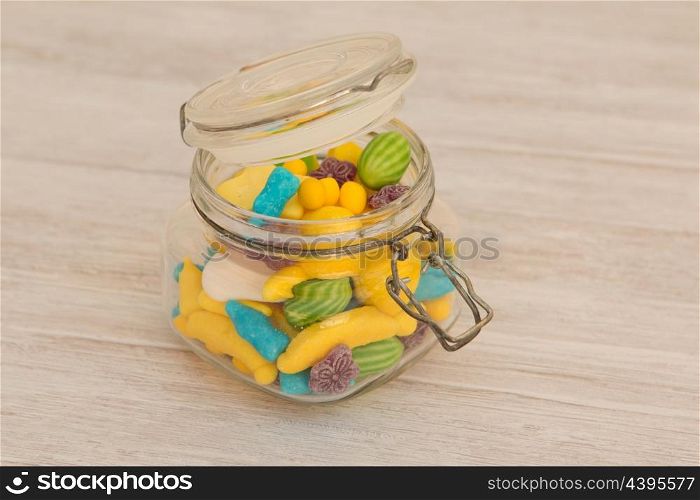 Container glass filled with candies on a gray wooden background