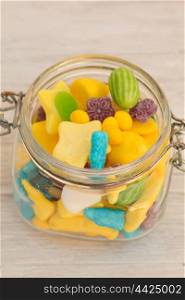 Container glass filled with candies on a gray wooden background