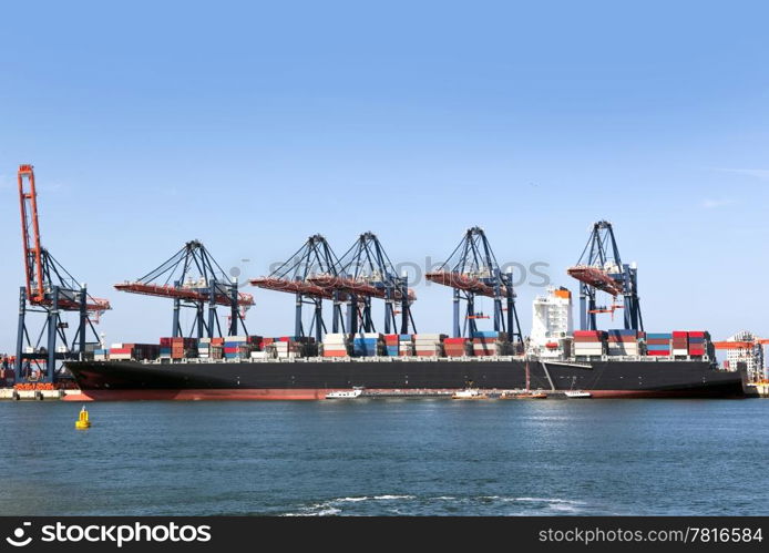 Container ship being unloaded at an industrial harbor