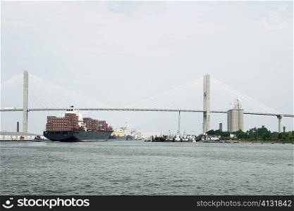 Container ship in a river with a suspension bridge in the background, Talmadge Bridge, Savannah River, Savannah, Georgia, USA