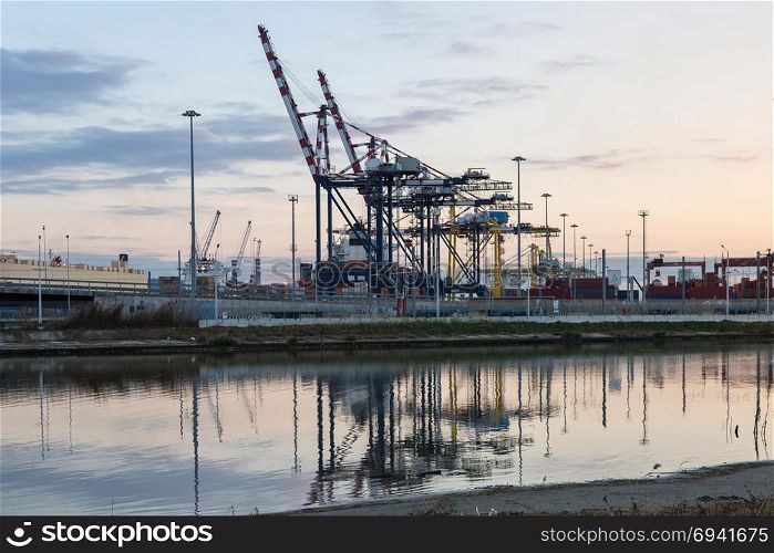 Container Terminal, Shipyard and Cranes at Sunset and Their Reflection.. Container Terminal, Shipyard and Cranes at Sunset and Their Reflection