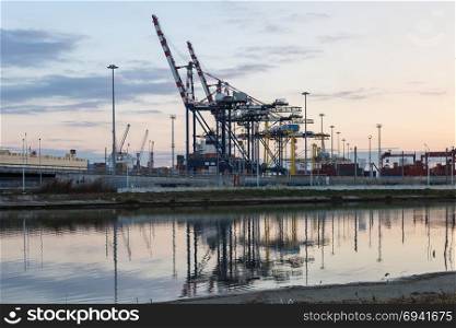 Container Terminal, Shipyard and Cranes at Sunset and Their Reflection.. Container Terminal, Shipyard and Cranes at Sunset and Their Reflection