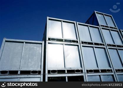 Containers stacked in silver rows over blue sky