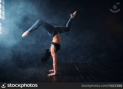 Contemp dance gymnastic exercise in studio. Female dancer stands on hands in ballroom. Contemp dance gymnastic exercise in studio