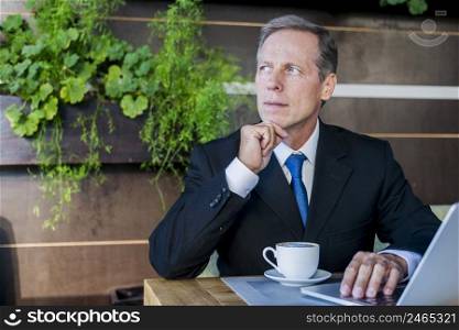 contemplated businessman sitting caf with cup coffee laptop desk