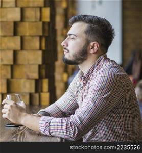 contemplated young man holding wineglass