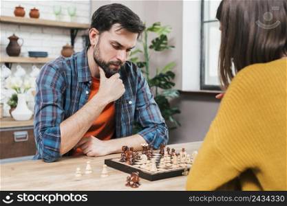 contemplated young man playing chess game with her wife home
