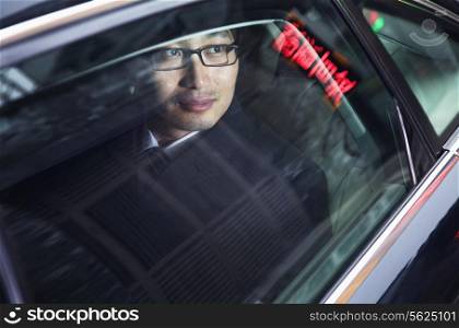 Contemplative businessman looking through car window at the night