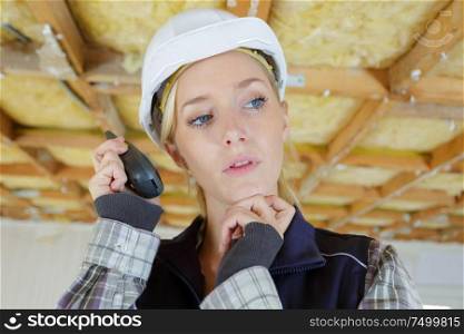 contemplative female builder using walkie talkie
