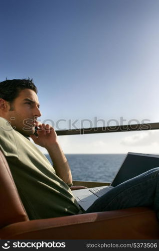 Contemplative man with a laptop by the ocean
