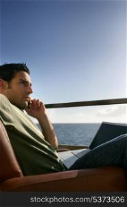 Contemplative man with a laptop by the ocean