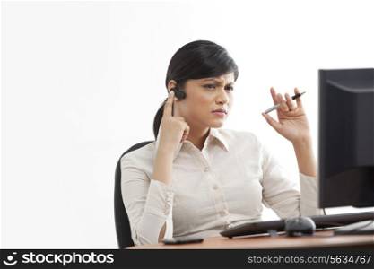 Contemplative young businesswoman on call while looking at computer