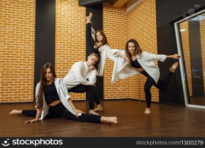 Contemporary dance group poses in studio. Female and male dancers training in class, modern grace dancing, stretching exercise. Contemporary dance group poses in studio