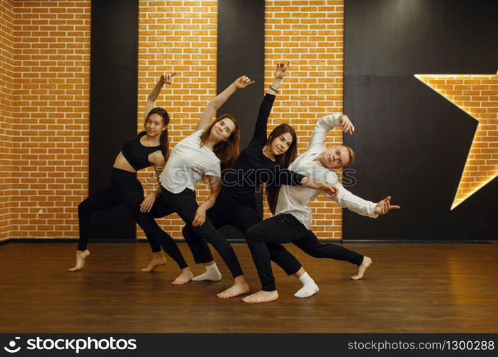 Contemporary dance performers in studio, snapshot in action. Female and male dancers training in class, modern grace dancing, stretching exercise, aerobic