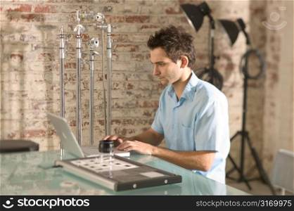 Contemporary Photographer Using His Laptop In The Studio