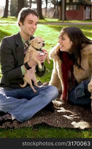 Contemporary Urban Couple Playing With A Puppy In The Park