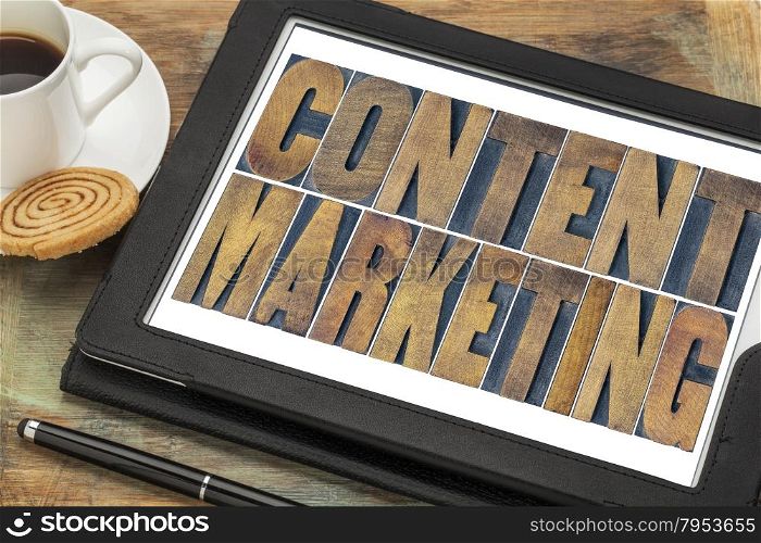 content marketing - text in grunge letterpress wood type printing blocks on a digital tablet with a cup of coffee