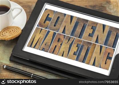 content marketing - text in grunge letterpress wood type printing blocks on a digital tablet with a cup of coffee