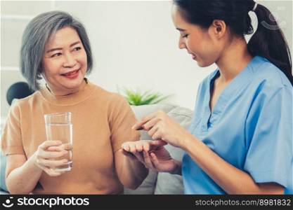 Contented senior woman taking medicines while her caregiver advising her medication. Medication for seniors, nursing house, healthcare at home.. A contented senior woman taking medicine.