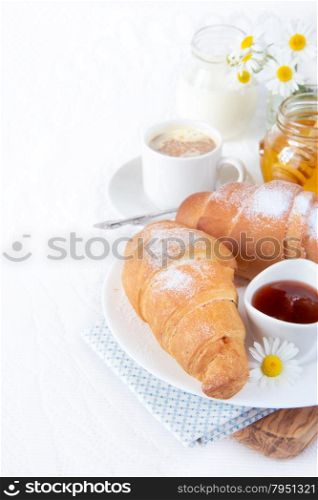 Continental breakfast with croissant, cup of coffee, jam and honey