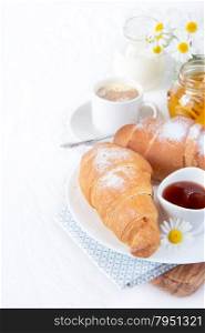 Continental breakfast with croissant, cup of coffee, jam and honey