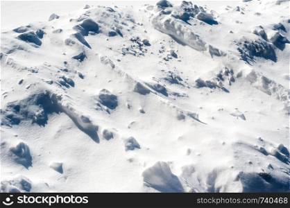Contoured white snow drift and chunks casting shadows.