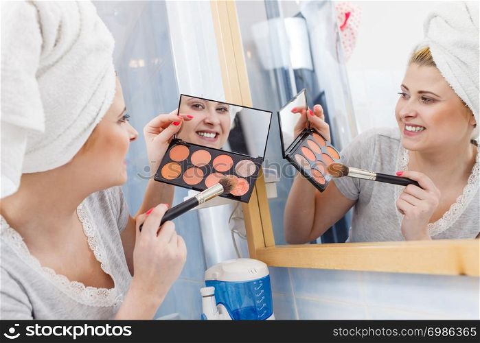 Contouring face kit, visage and make up concept. Woman in bathroom applying contour bronzer on brush. Woman in bathroom applying contour bronzer on brush