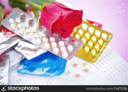 Contraceptive pill and Condom Prevent Pregnancy Contraception Valentines safe sex concept / Birth Control with Condom and roses on calendar background - Stop pregnancy or sexually transmitted disease