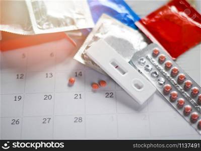 Contraceptive pill and Pregnancy Tests Prevent Pregnancy Contraception concept / Birth Control with Condom on calendar background - health care and medicine