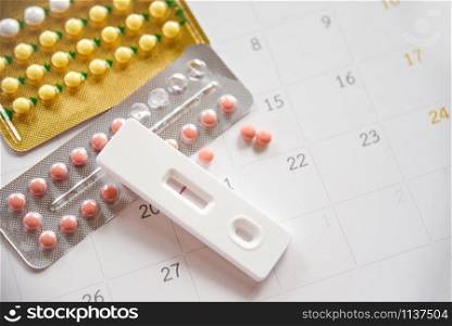 Contraceptive pill and Pregnancy Tests Prevent Pregnancy Contraception concept / Birth Control with Condom and roses on calendar background - health care and medicine