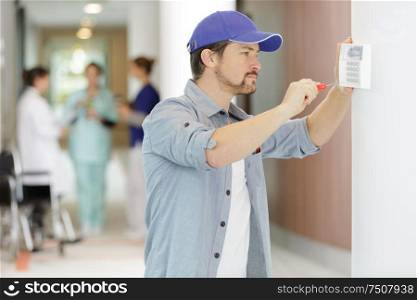 contractor fixing keypad to wall in hospital