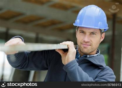 contractor in hard hat holding plank of wood