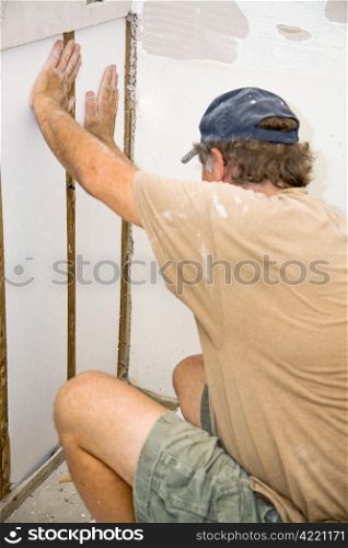 Contractor installing styrofoam insulation in a section of wall he is replacing. Authentic and accurate content depiction.