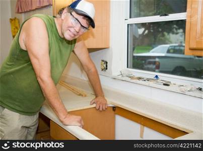 Contractor remodeling a kitchen, leaning over the laminate counter top.