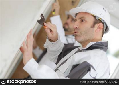Contractor removing wallpaper with a scraper