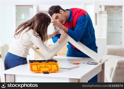 Contractor repairman assembling furniture under woman supervision