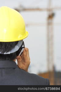 . Contractor Wearing A Hardhat On The Phone Inspecting His Building Site