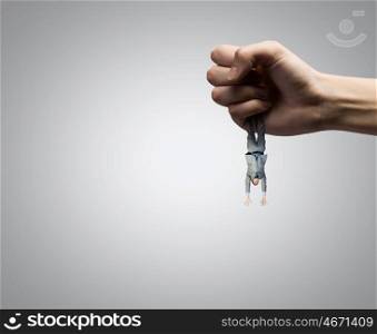 Control and power. Close up of big human hand catching businessman