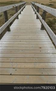 Converging wooden bridge with handrails. Chesil Beach, Weymouth, Dorset, England, United Kingdom.