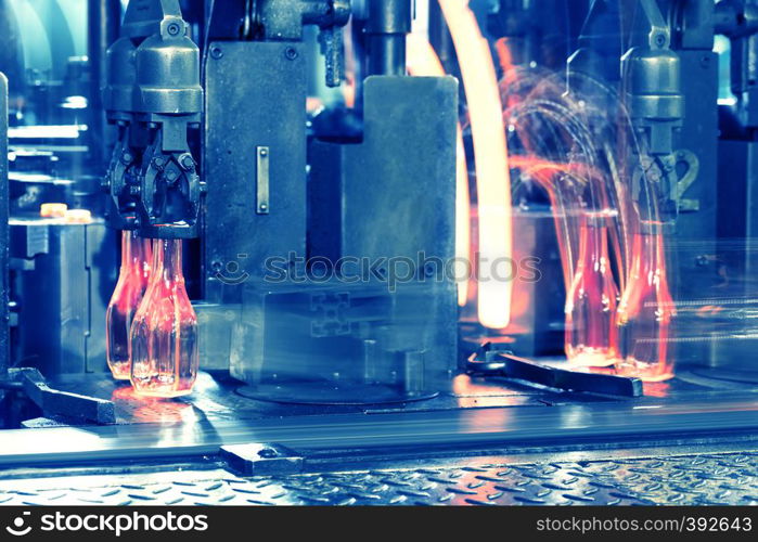 Conveyor with the hot glass bottles. Hot red bottles move along the conveyor at the glass factory. Toning. Conveyor with the hot glass bottles