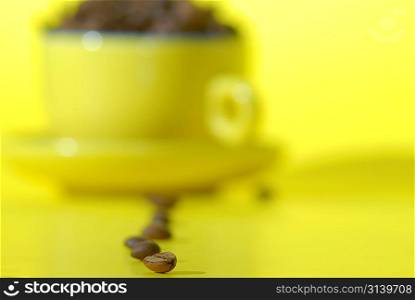 cooffee beans and cup on yellow background