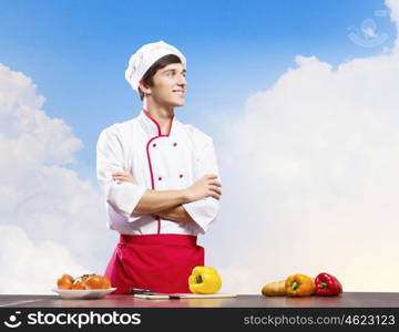 Cook at kitchen. Young cheerful cook and ingredients flying in air