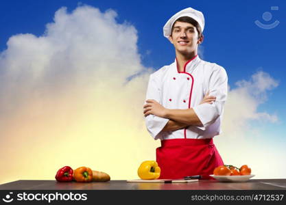 Cook at kitchen. Young cheerful cook and ingredients flying in air