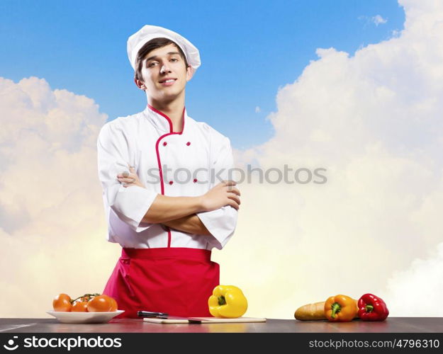 Cook at kitchen. Young cheerful cook and ingredients flying in air