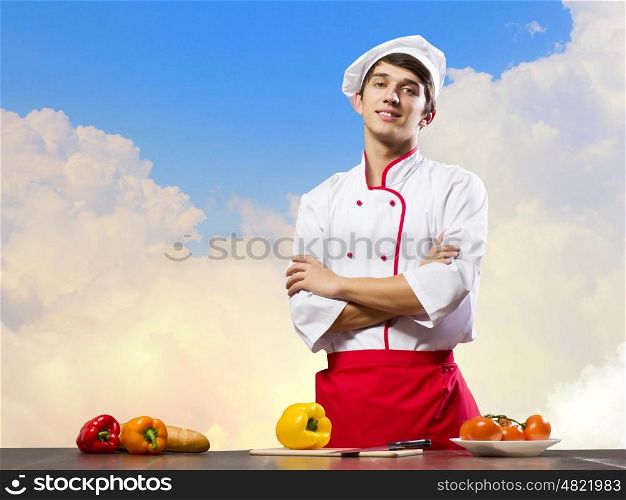 Cook at kitchen. Young cheerful cook and ingredients flying in air