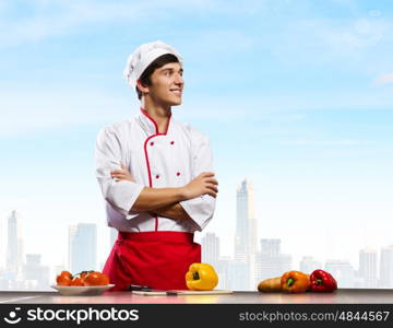 Cook at kitchen. Young cheerful cook and ingredients flying in air