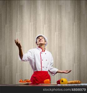 Cook at kitchen. Young cheerful cook and ingredients flying in air