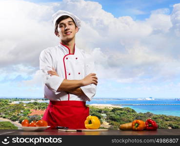 Cook at kitchen. Young cheerful cook and ingredients flying in air