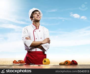 Cook at kitchen. Young cheerful cook and ingredients flying in air