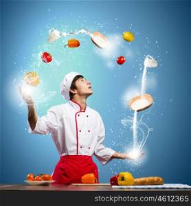 Cook at kitchen. Young man at kitchen juggling with ingredients